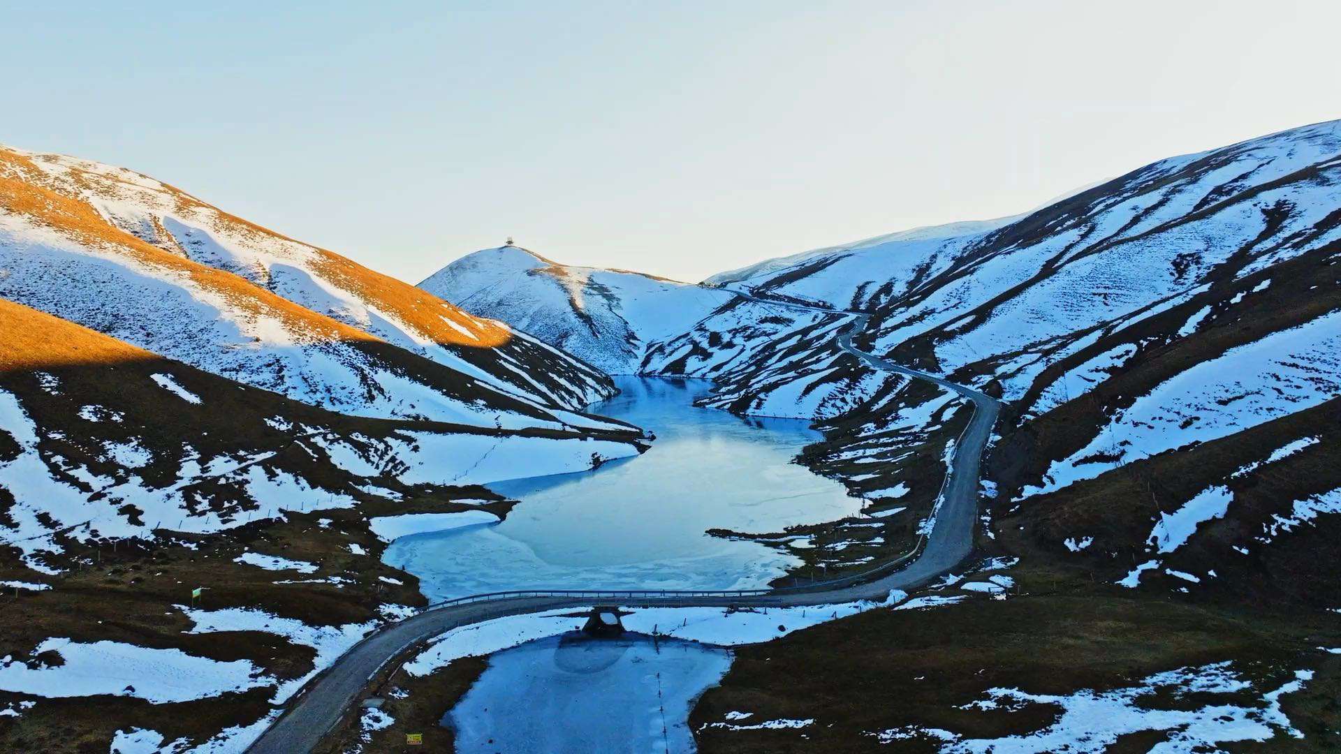 大海草山夕阳下结冰的湖面积雪的草山航拍，视频素材：画视记官网
